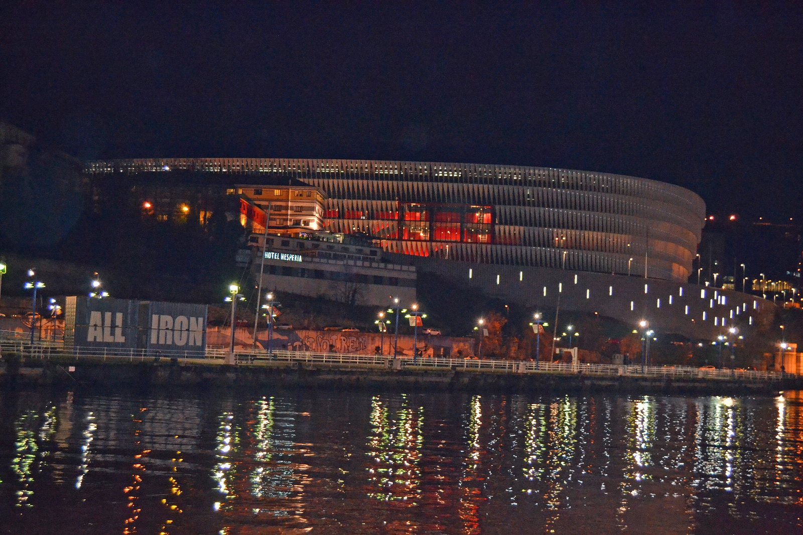 San Mamés de noche, blanco por fuera y rojo por dentro, con la ría delante. Foto: Euskaldunaa (CC BY-SA 4.0), Wikimedia Commons.